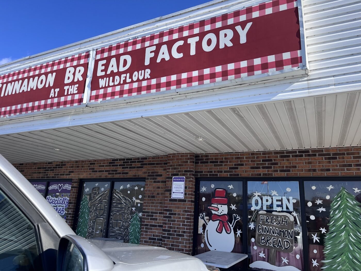 The gingham Cinnamon Bread Factory storefront sign with OPEN — Fresh Cinnamon Bread window art